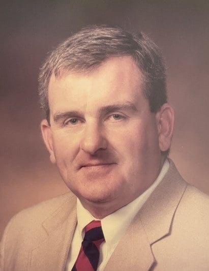 Portrait of a man in a beige suit and tie.
