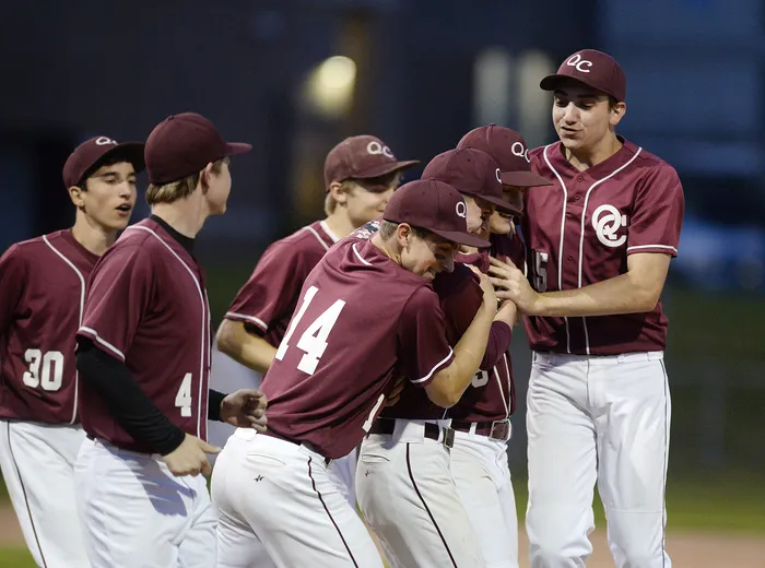 Baseball players in maroon uniforms celebrating on the field.