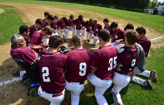 High school football team kneeling in a circle, praying before the game.