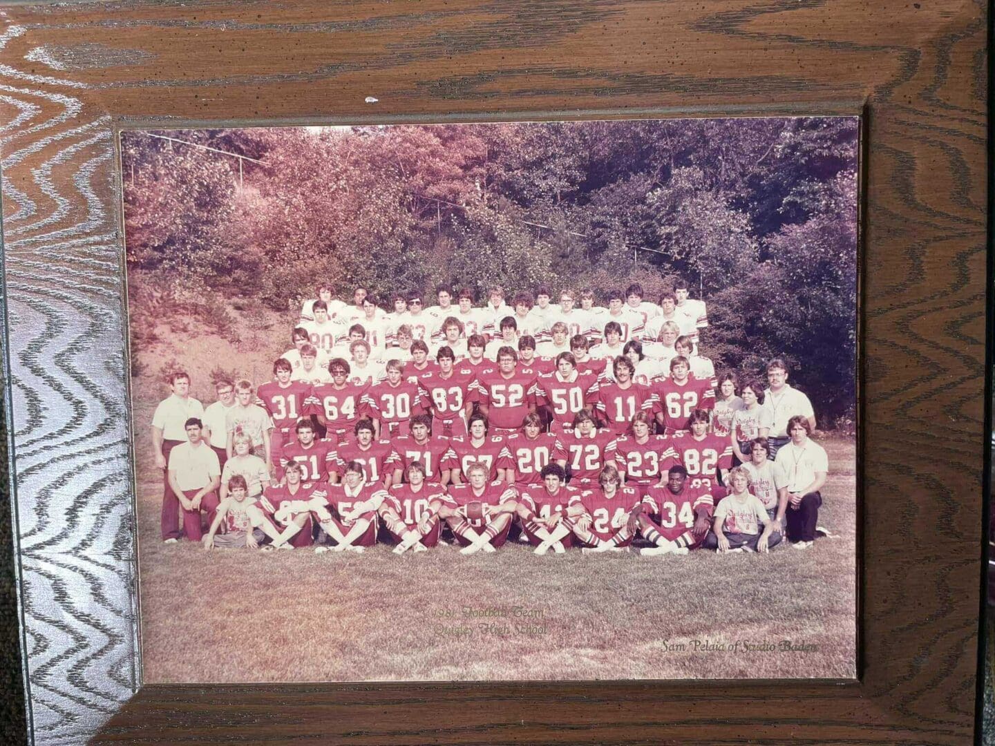 High school football team posing for a group photo on a field.
