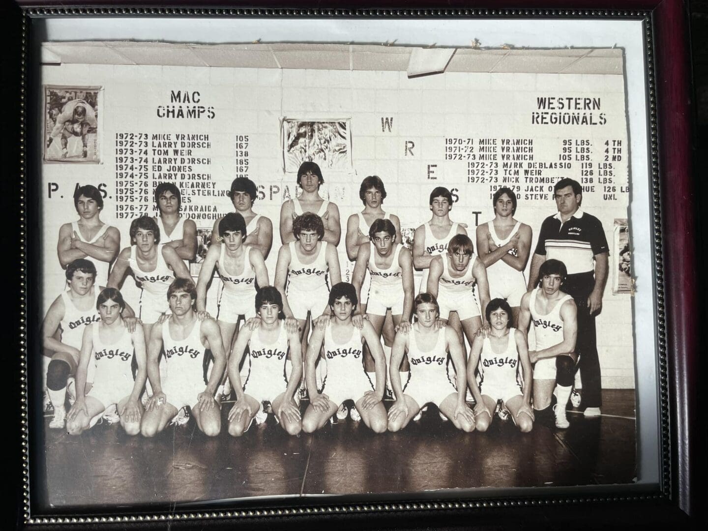 Black-and-white photo of a youth basketball team posing with coaches in a gym.