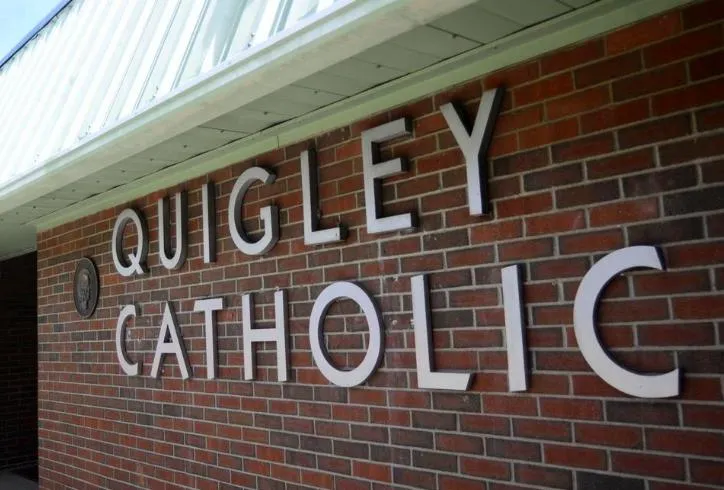 Sign on a brick wall reading 'Quigley Catholic'.