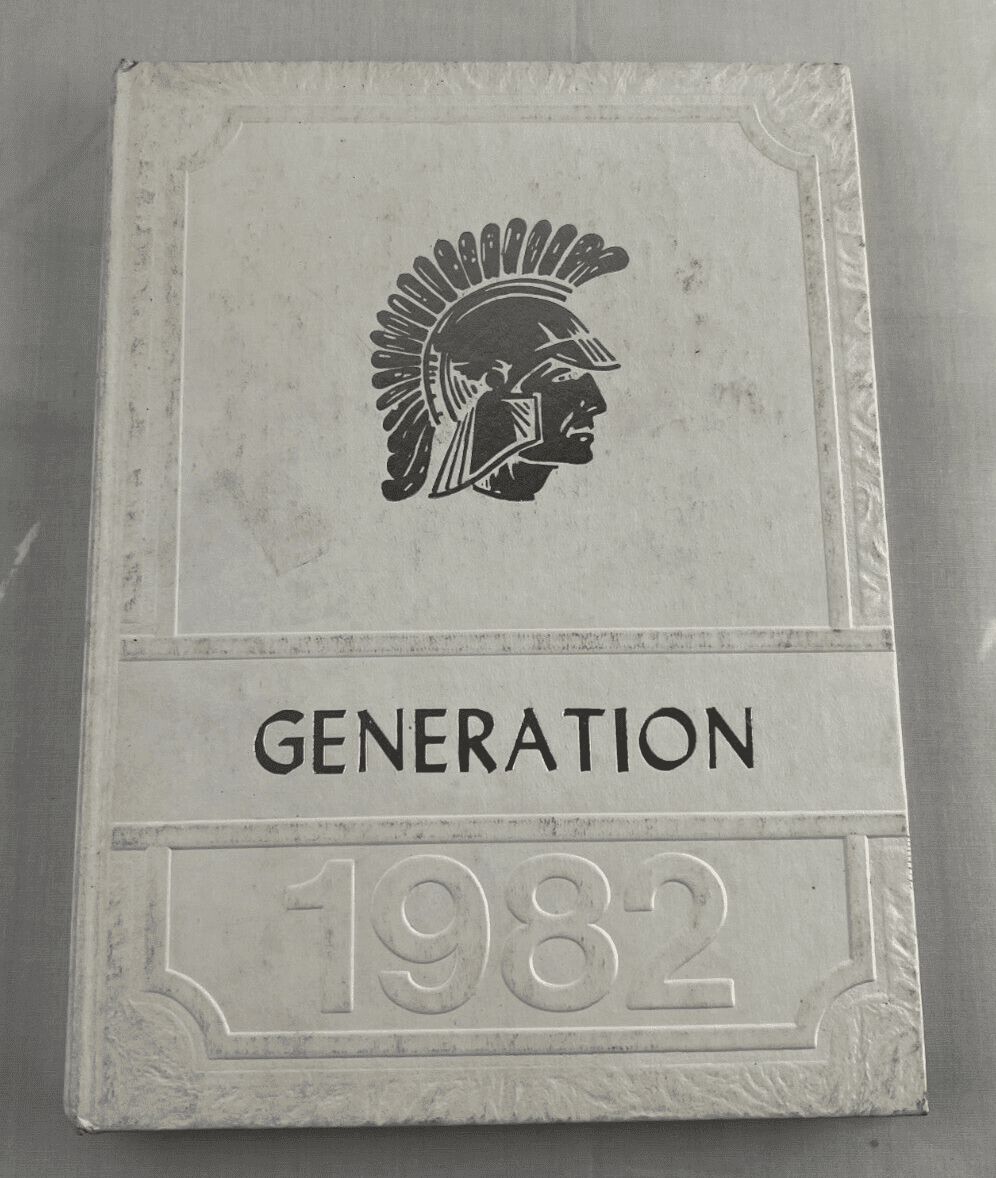 A carved stone plaque with a Spartan helmet and 'GENERATION 1982' inscription.