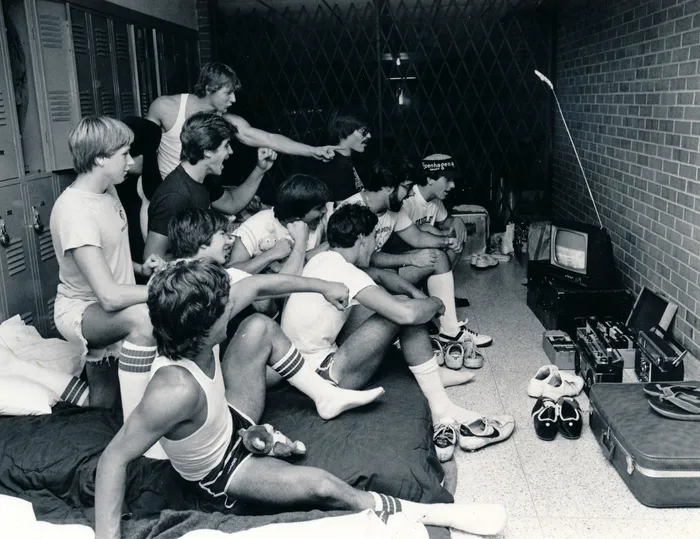 A group of young boys watching TV intently in a casual room setting.