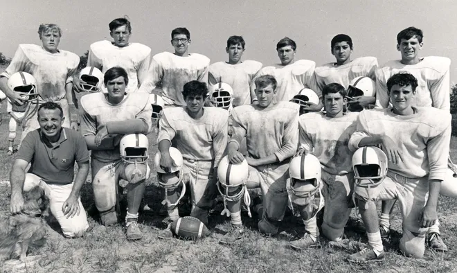 Black and white photo of a vintage football team posing on a field.