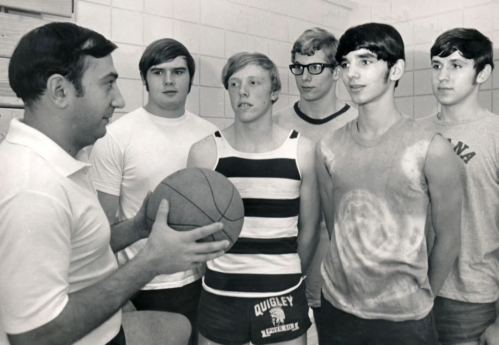 Vintage black and white photo of a basketball coach instructing young players.